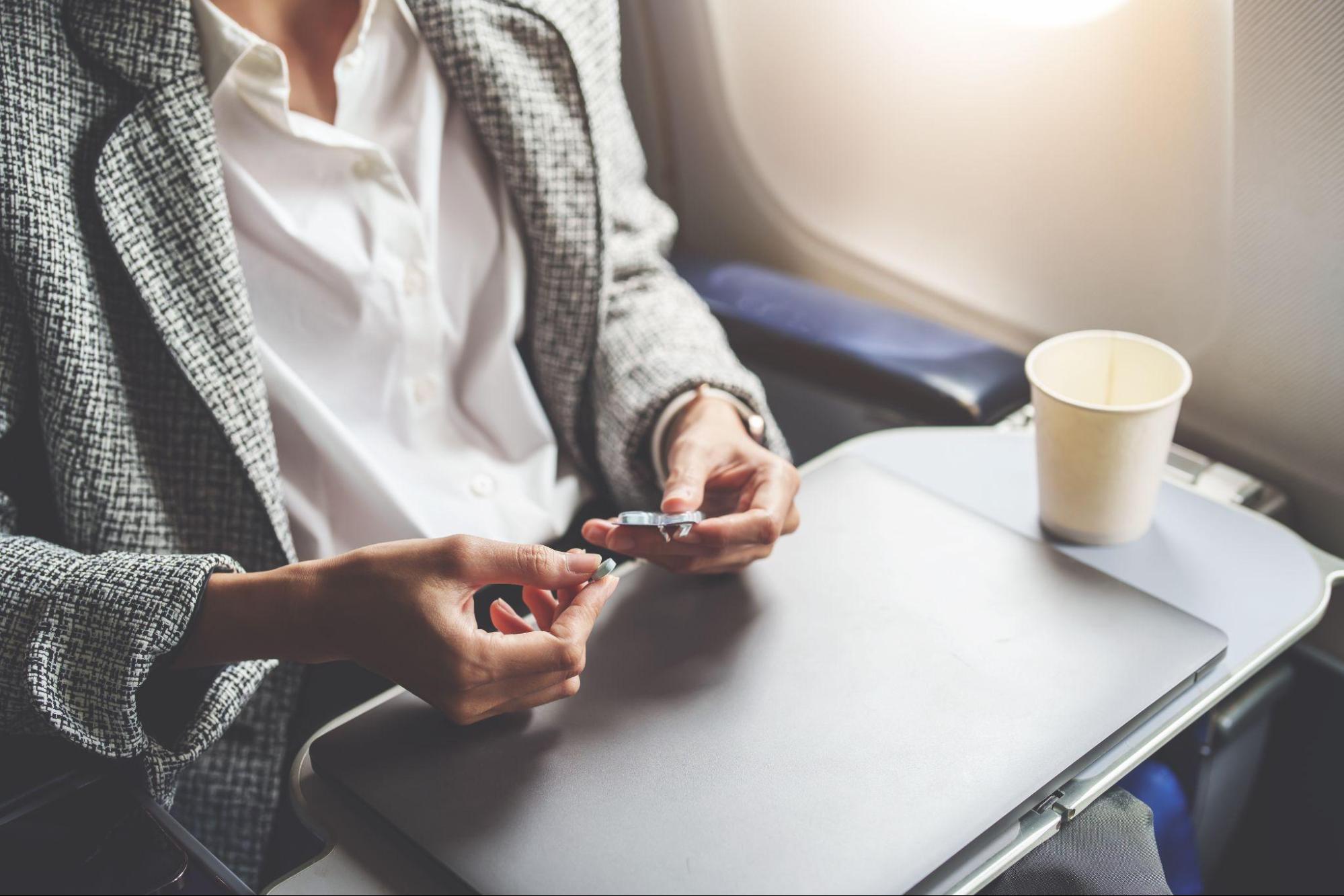 Eine Frau, die in einem Flugzeug sitzt, öffnet ein Tablet-Paket auf ihrem Tabletttisch