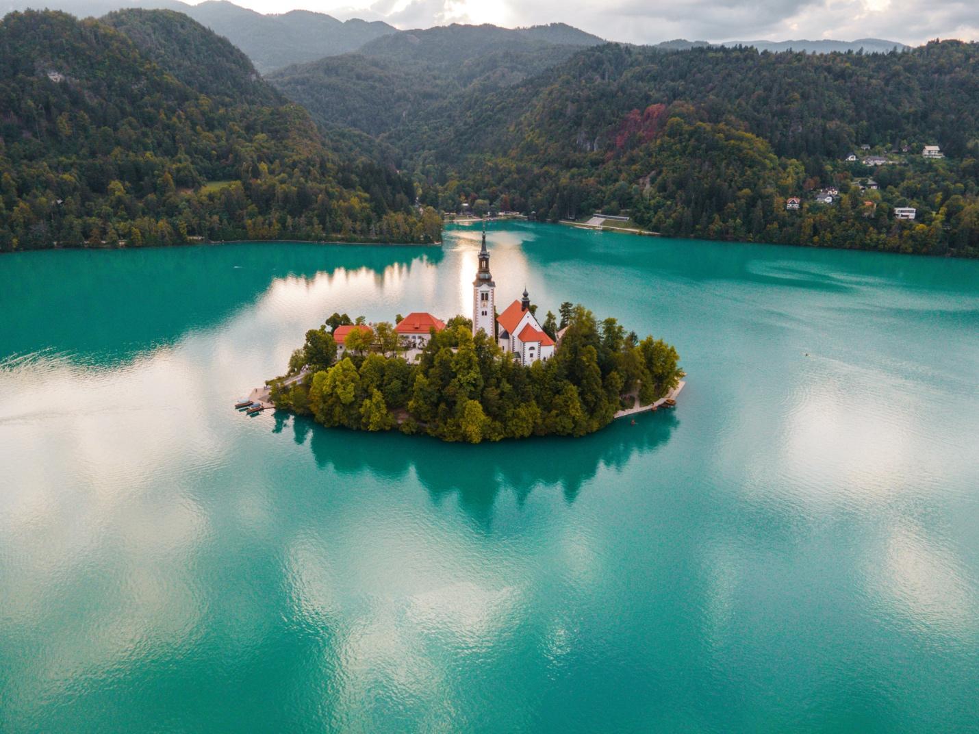Die Maria-Königin-Kirche liegt auf einer kleinen Insel inmitten des Bleder Sees in Slowenien, umgeben von dichtem Wald.