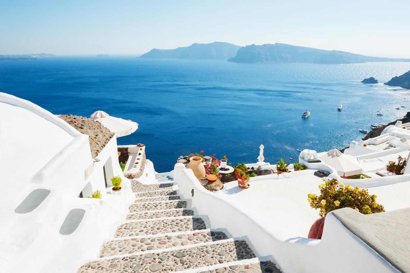 Leuchtend weiße Häuser auf einer griechischen Insel liegen hoch über dem blauen Ozean